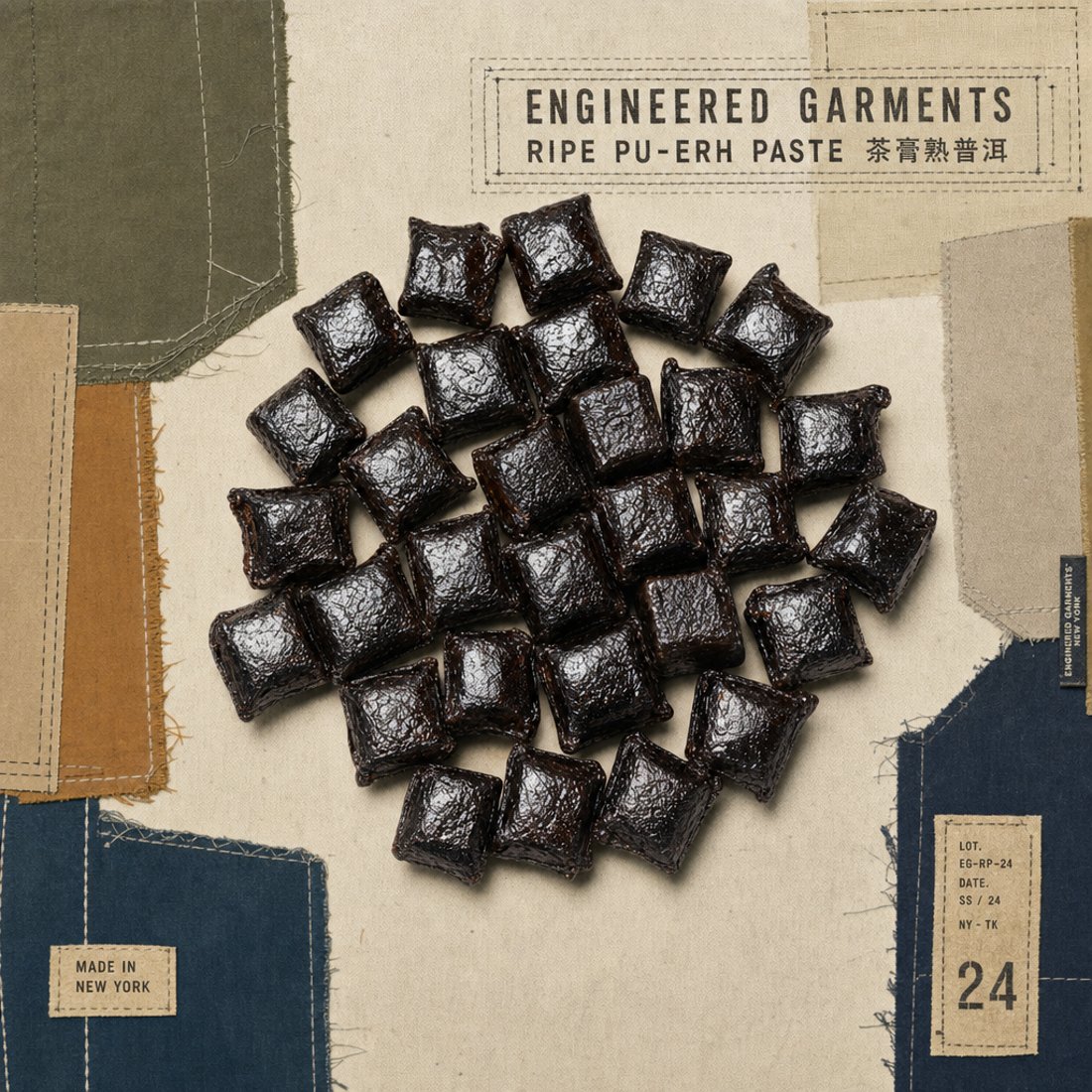Dark cubes of pressed pu-erh paste arranged on patched olive and denim cloth with white running stitch and a mono utility caption